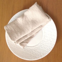 Serviette de table grège et écologique en lin naturel dans une assiette blanche